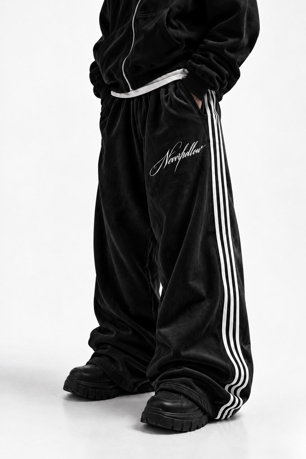 Drift Track Pants Obsidian, worn, front view, with white side stripes and the Neverhollow script on the front