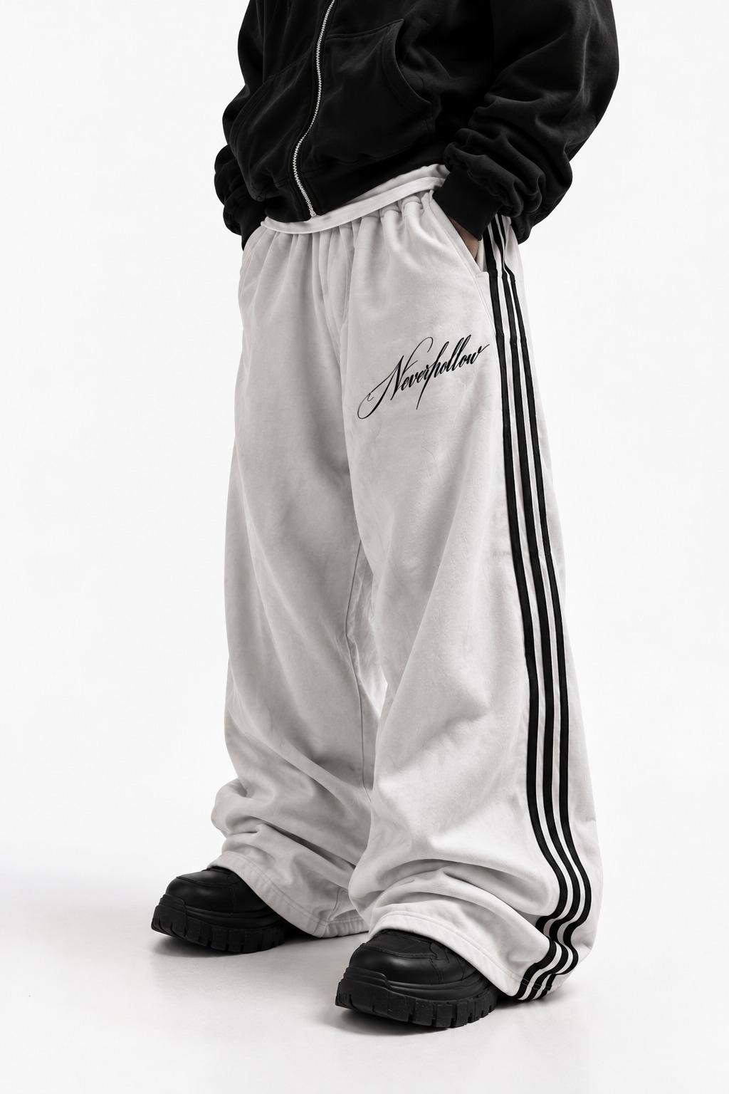 Drift Track Pants Bone, worn, front view, with black side stripes and the Neverhollow script on the front