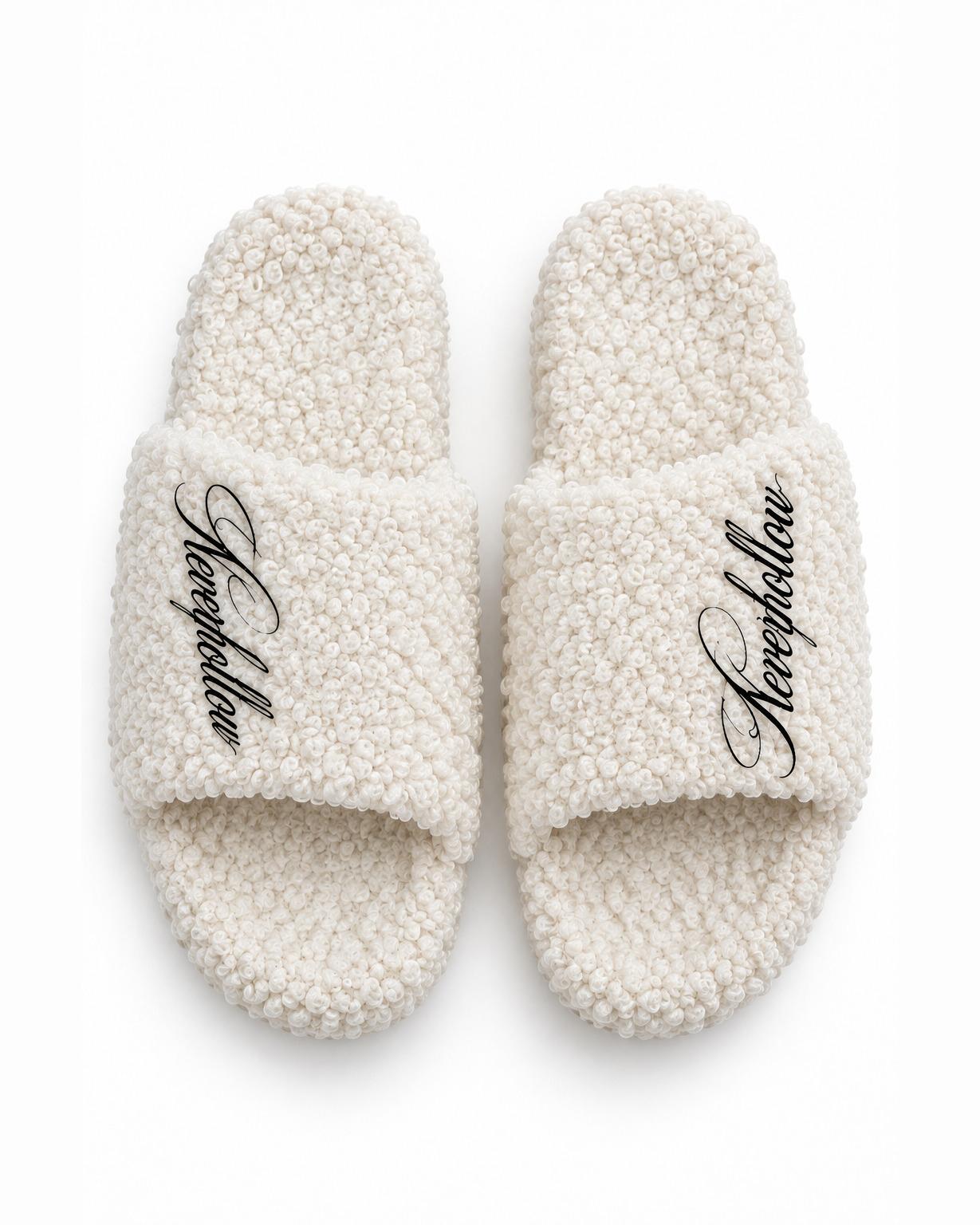 A pair of Haven Slides Bone seen from above, with the Neverhollow script on each strap